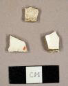 Whiteware sherds, one with red hand painted design, and one white kaoline pipe bowl fragment