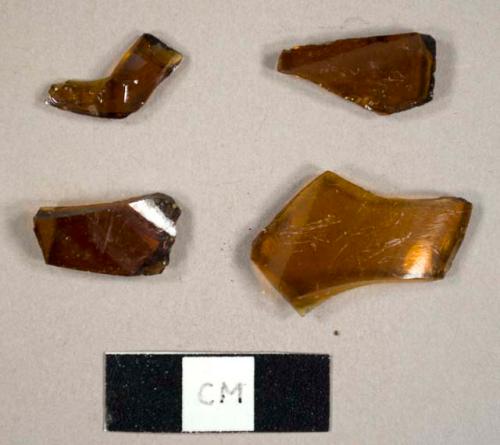 Amber  bottle glass fragments, one with embossed "T" on exterior