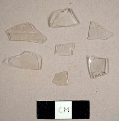 Colorless curved glass fragments, possibly from a hurricane lamp