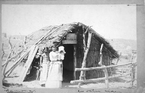 Two women standing outside structure. "Ramona" (44-40-10/96630.1)