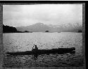 Aleut man in kayak with mountains in the background
