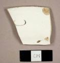 Whiteware rim sherd to a bread plate with a hand painted floral design in black and green on the marly