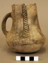 Ceramic pitcher, incised handle, black on white exterior, depressed base, mended