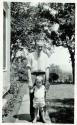 Scan of page from Judge Burt Cosgrove photo album.  Man and child standing.