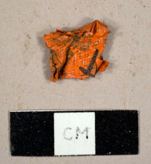 Orange plastic flagging tape fragment