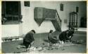 Scan of photograph from Judge Burt Cosgrove photo album.Men praying in Santo Toma's woman watching rose petals and candles on the floor