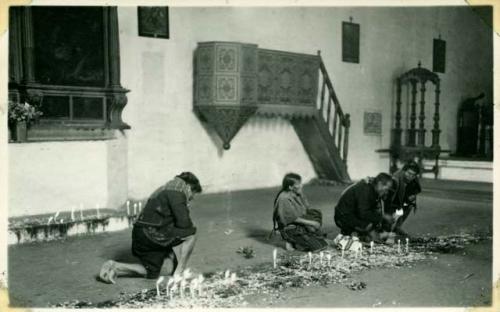 Scan of photograph from Judge Burt Cosgrove photo album.Men praying in Santo Toma's woman watching rose petals and candles on the floor