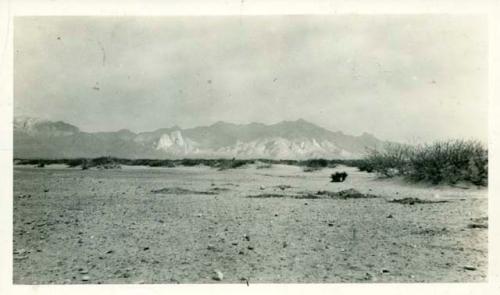 Scan of photograph from Judge Burt Cosgrove photo album.East side of Organ Mts., NW of camp at ruin above El Paso. Foreground shows ruin about obliterated by flood waters
