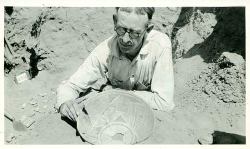 Scan of photograph from Judge Burt Cosgrove photo album.Assembling broken bowl. Swarts Ruin 1925