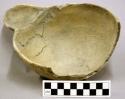 Ceramic plain bowl with concave handle and broken off sherds