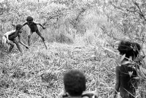 Samuel Putnam negatives, New Guinea.A child raises a spear to throw it at the hoop