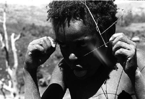Samuel Putnam negatives, New Guinea. Tukom playing with grass across his face