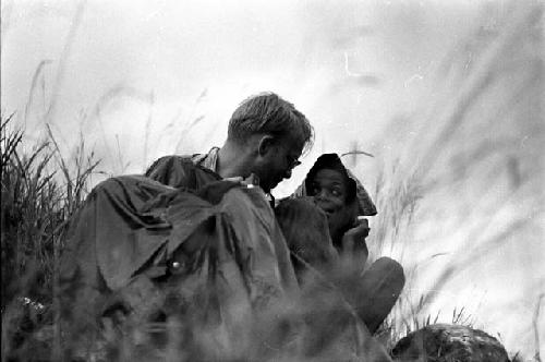 Samuel Putnam negatives, New Guinea. MR huddled with some small boys as it began to rain out on the field