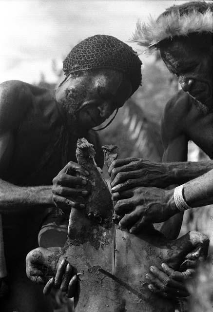 Men cutting pig meat