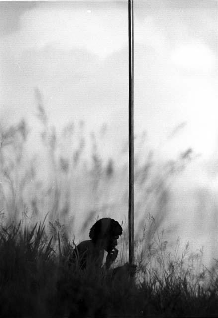 Samuel Putnam negatives, New Guinea; a man sits with 2 spears waiting for the battle to develop