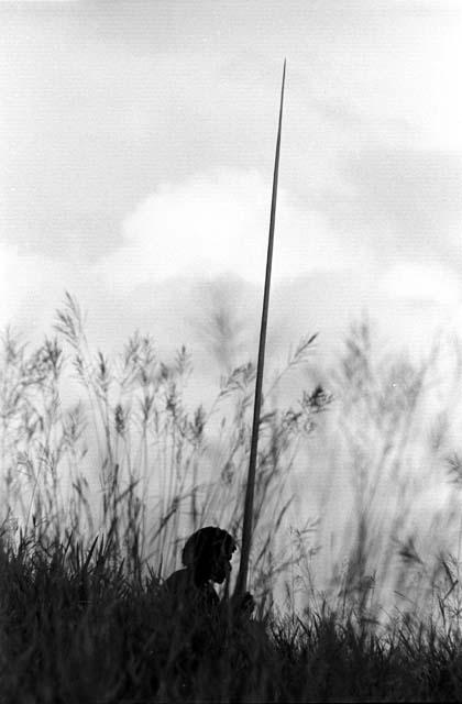 Samuel Putnam negatives, New Guinea;  a man sits with 2 spears waiting for the battle to develop