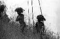 Samuel Putnam negatives, New Guinea; 2 older warriors; grass on to protect themselves from the rain; waiting for the battle to develop