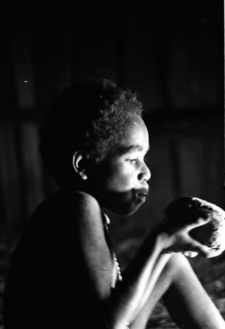 Samuel Putnam negatives, New Guinea; Uwar eating a sweet potatoe in honai