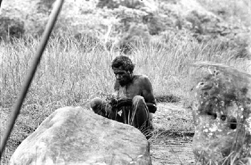 Samuel Putnam negatives, New Guinea; man sits on the Anelerak; starting a fire