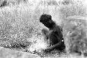 Samuel Putnam negatives, New Guinea; man sits on the Anelerak; starting a fire