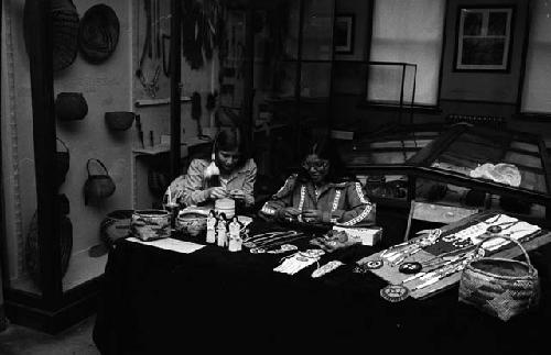 Girls, seated, busy at work making bead ornaments