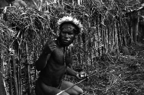 Samuel Putnam negatives, New Guinea; Tege Warek; talking to somebody; fixing his spear