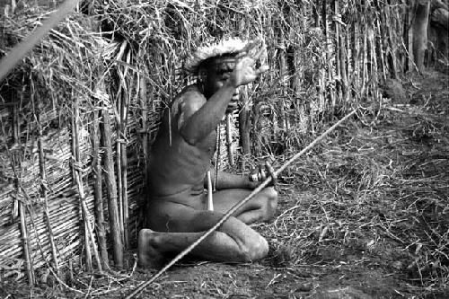 Samuel Putnam negatives, New Guinea; Tege Warek; talking to somebody; fixing his spear