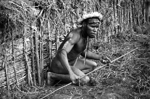 Samuel Putnam negatives, New Guinea; Tege Warek; talking to somebody; fixing his spear