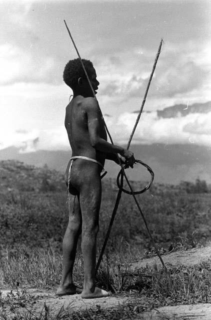 Samuel Putnam negatives, New Guinea; Isili stands with spears and a hoop; playing Sikoko wasin