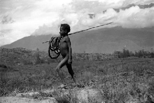 Samuel Putnam negatives, New Guinea; young boy with many hoops in his spear; he is going home