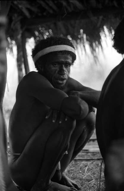 Samuel Putnam negatives, New Guinea; man squats under an olea
