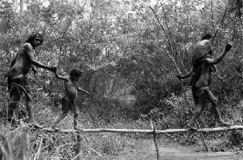 Samuel Putnam negatives, New Guinea; women walking across a small bridge