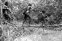 Samuel Putnam negatives, New Guinea; women walking across a small bridge