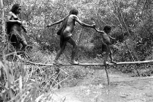 Samuel Putnam negatives, New Guinea; women walking across a small bridge