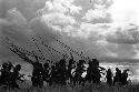 Samuel Putnam negatives, New Guinea; on the Liberek; Etai; a large group of men running silhouette against clouds on Liberek