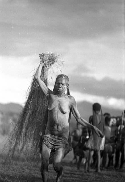 Samuel Putnam negatives, New Guinea; a woman trailing a great deal of grass running towards the camera