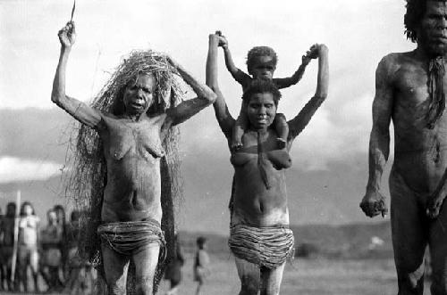 Samuel Putnam negatives, New Guinea; a woman with the grass on her head; mother with child on her shoulders and a man; not well framed; run towards camera