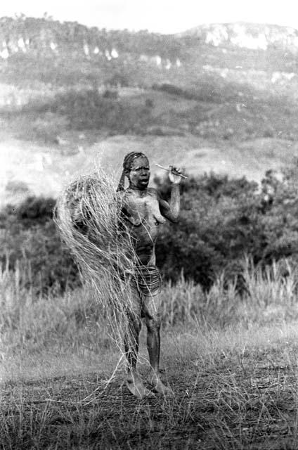 Samuel Putnam negatives, New Guinea; a woman dances along; bundle of grass on her head