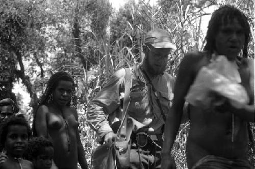 Samuel Putnam negatives, New Guinea; MR surrounded by women walking on a path towards the Etai in Kurelu area