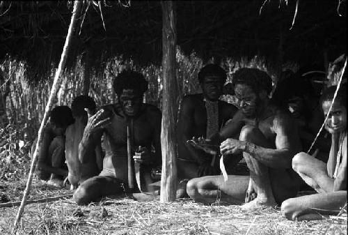 Samuel Putnam negatives, New Guinea; group of men knitting nyeraken are under an olea