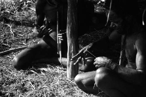 Samuel Putnam negatives, New Guinea; group of men knitting nyeraken are under an olea