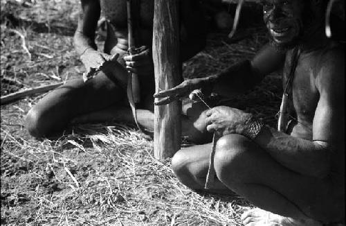 Samuel Putnam negatives, New Guinea; group of men knitting nyeraken are under an olea