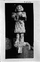 Statue - humanlike figure: raised palms, skirt of snakes (?)