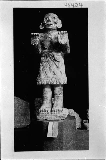 Statue - humanlike figure: raised palms, skirt of snakes (?)