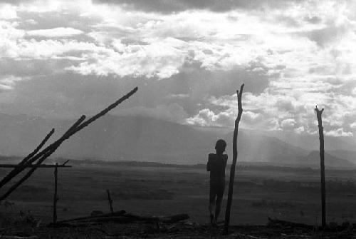 Samuel Putnam negatives, New Guinea; a boy against the skyline up with the partially finished structure where they gather wood