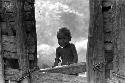 Samuel Putnam negatives, New Guinea; a little boy stares from the entrance to a sili