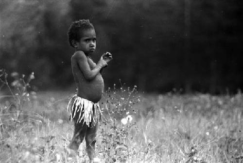 Samuel Putnam negatives, New Guinea; little girl in field; weeds; in front of her