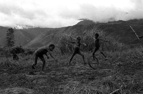 Samuel Putnam negatives, New Guinea; boys playing sikoko wasin; hoop rolling past; spears