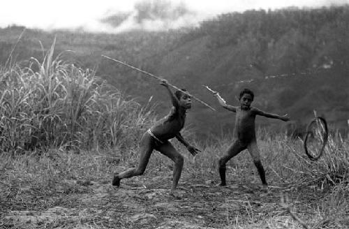 Samuel Putnam negatives, New Guinea; boys playing sikoko wasin; hoop rolling past; spears