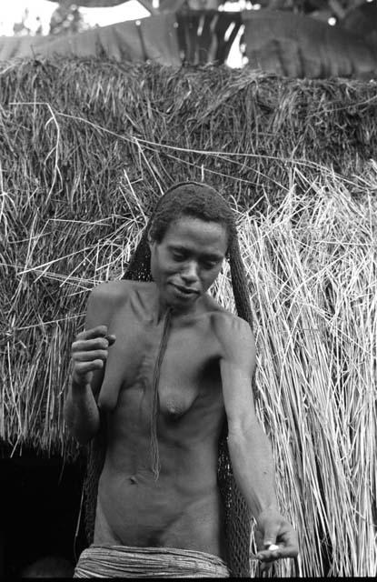 Samuel Putnam negatives, New Guinea; a woman outside of ebai in Abulupak; handing something to someone